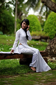 woman in white traditional dress sitting on bench during daytime