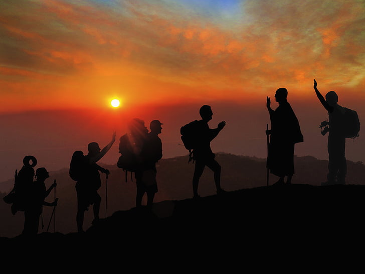 silhouette of people climbing mountain