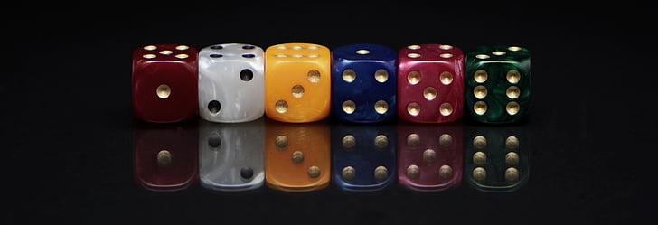 six assorted-colored dies on black surface