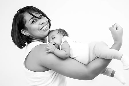 grayscale photo of woman carrying baby with her arm