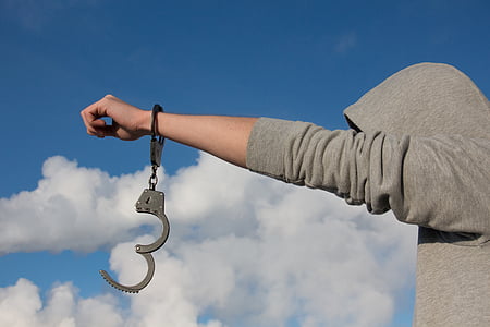 person in gray hoodie with handcuffs during daytime