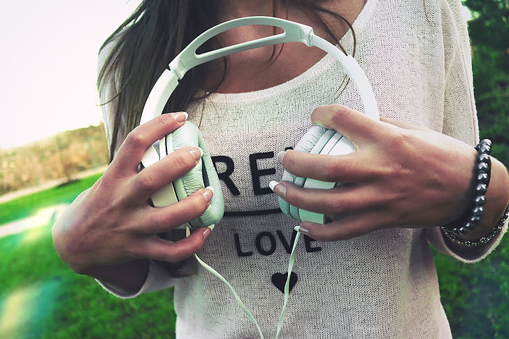 woman holding white corded headphones