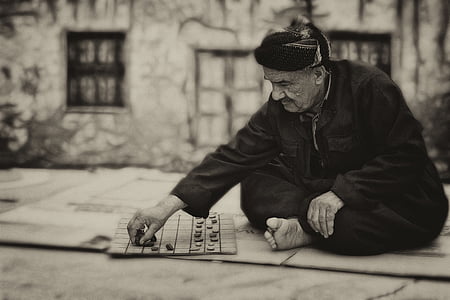 grayscale photography of man playing checkers