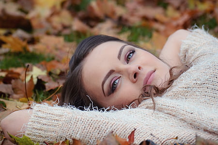 woman portrait wearing sweater laying in leaves