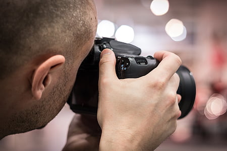 person using black DSLR camera in shallow focus photographty