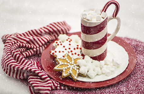 white and red ceramic mug on saucer with cookies