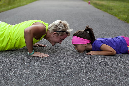 woman having a push-up in front of girl during daytime