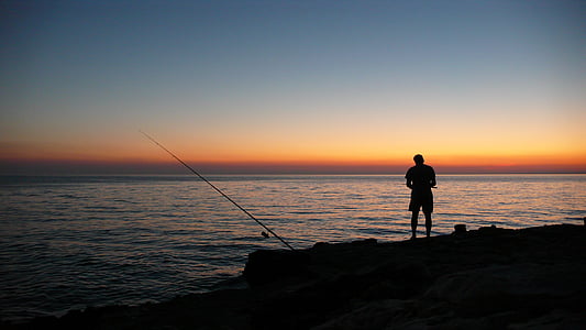 silhouette of a man near body of water