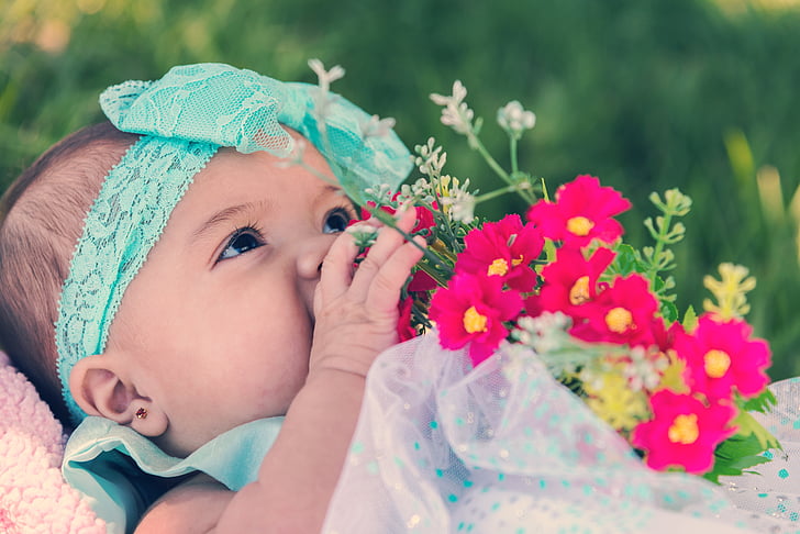 baby in white and blue dress holding flower bouquet