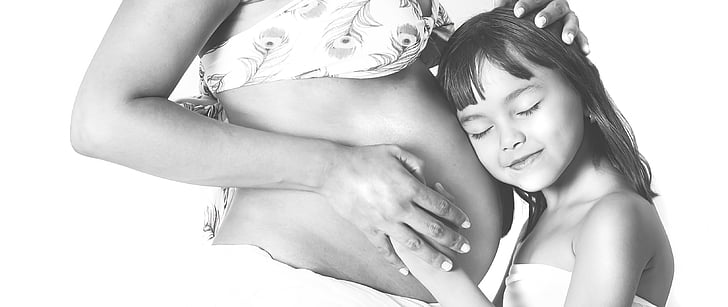 girl in white tube dress holding pregnant woman tummy