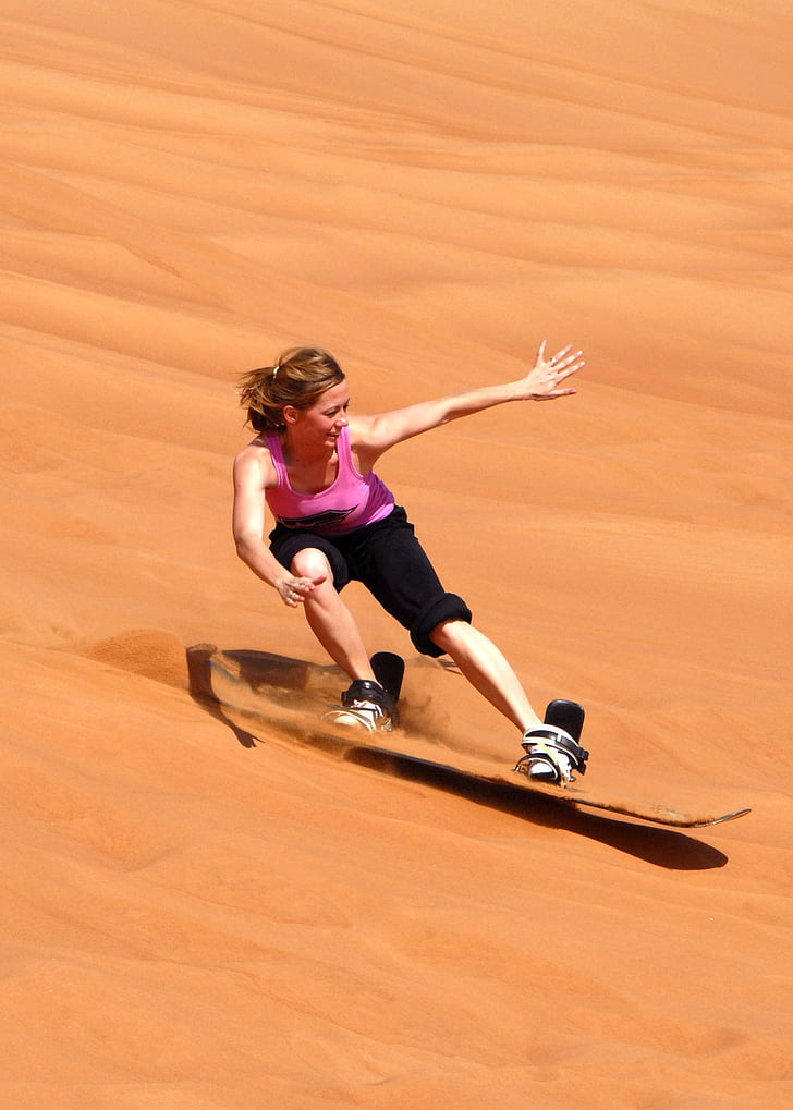 woman in pink tank top and black pants sand skiing