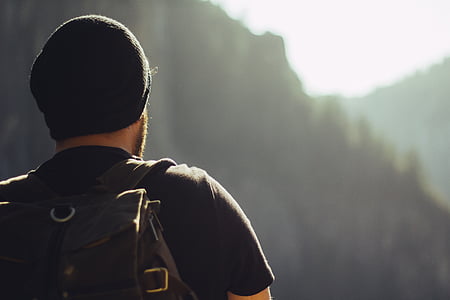 man in black t-shirt, black beanie, and brown backpack