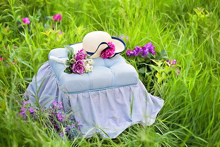 square tufted white fabric ottoman with sunhat on green grass field