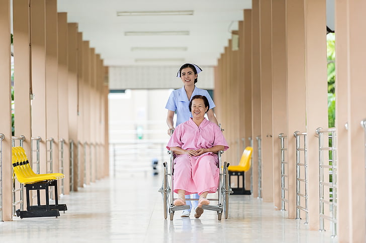 woman seating on wheelchair assisted by nurse