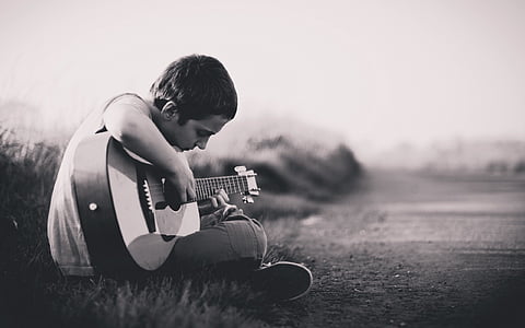 grayscale photography of boy playing guitar