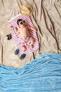 baby lying on red and white blanket with summer-themed photography