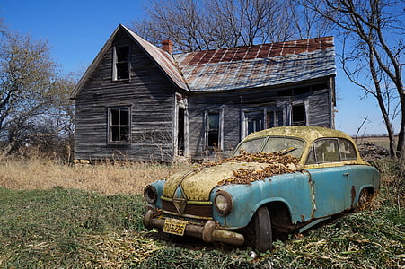 classic teal and beige car near abandoned brown wooden house