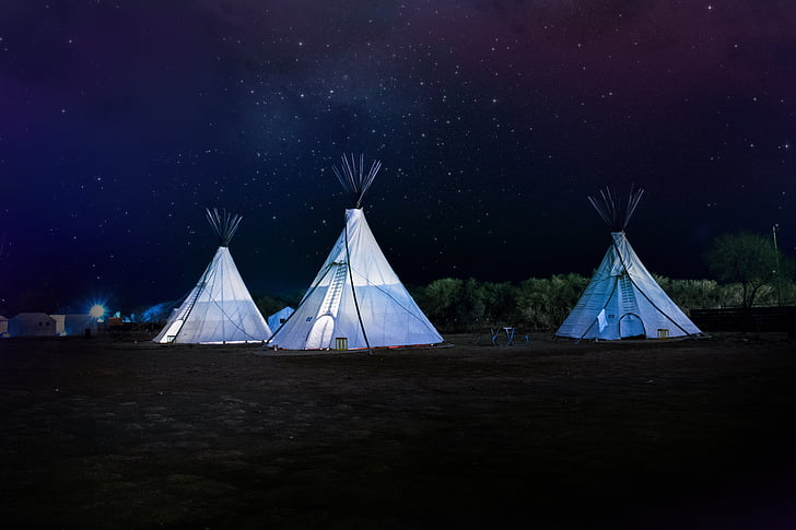 three white tipi outdoor tents at nighttime