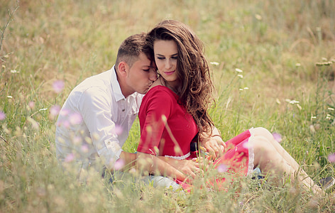 man and woman sitting on grass field during daytime