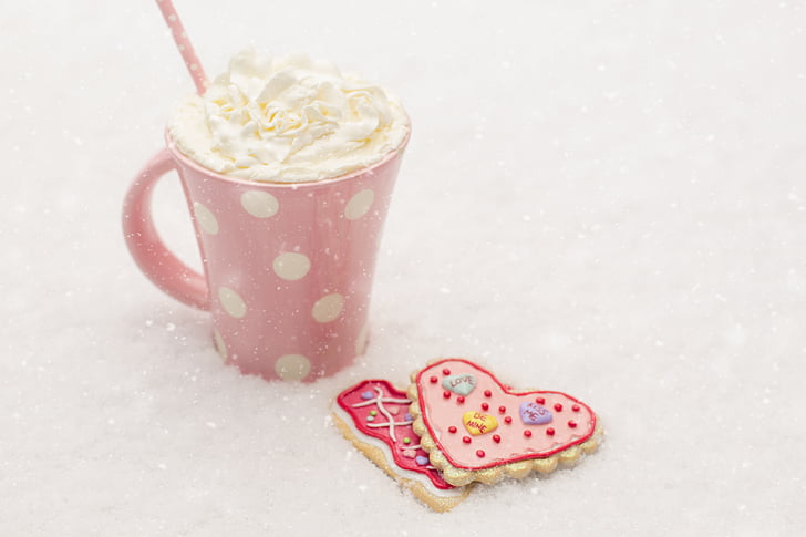 two heart shaped cookies beside whip cream served on white and pink polka dot mug