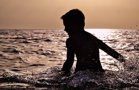 silhouette of boy swimming during sunset