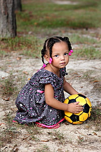 girl wearing gray floral dress holding yellow soccer ball