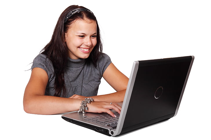 woman in gray shirt smiling while using black laptop computer