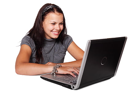woman in gray shirt smiling while using black laptop computer