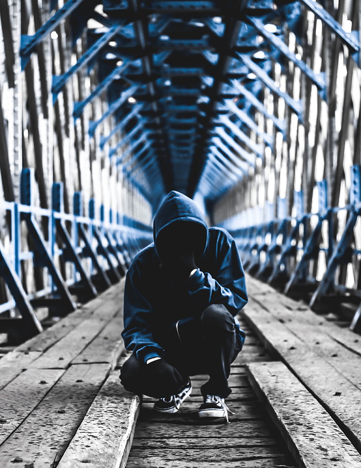 man wearing blue hoodie and black pants in bridge photography