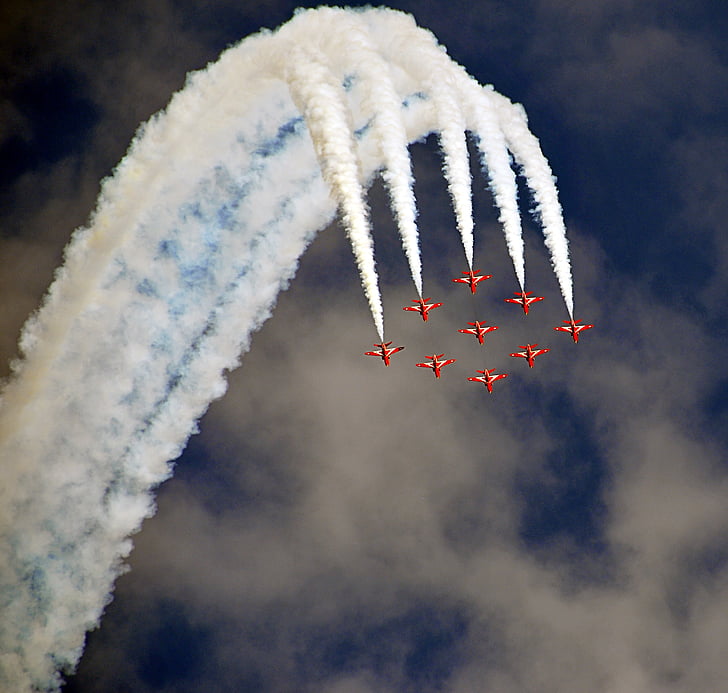 nine red jet plane with doing air shore during daytime
