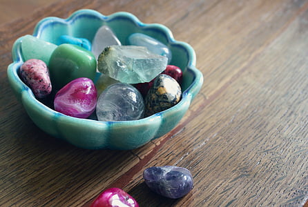 assorted-color rock collection on and beside teal ceramic bowl