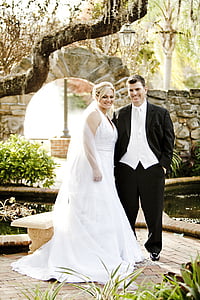 woman wearing white wedding dress and man wearing wedding outfit smiling