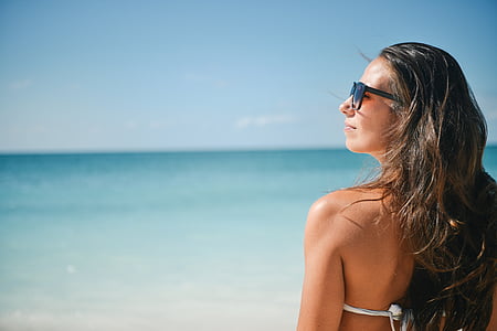 woman in white bikini top and black sunglasses at beach during daytime