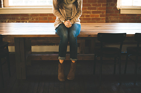 woman sitting on brown wooden table near window inside room