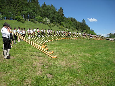 group of people standing and holding horns on the green grass