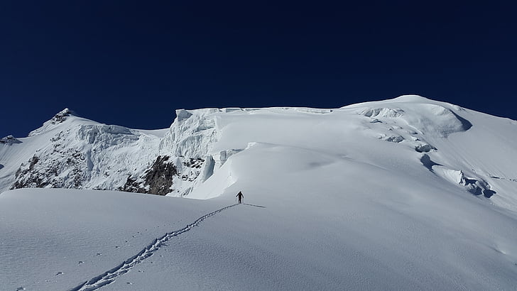 person walking on snow capped mountain