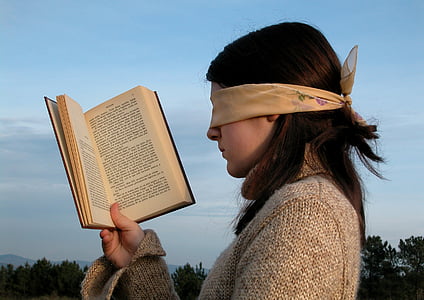 woman wearing white blindfold holding book during daytime