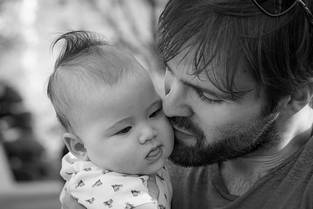 grayscale photography of man kissing baby