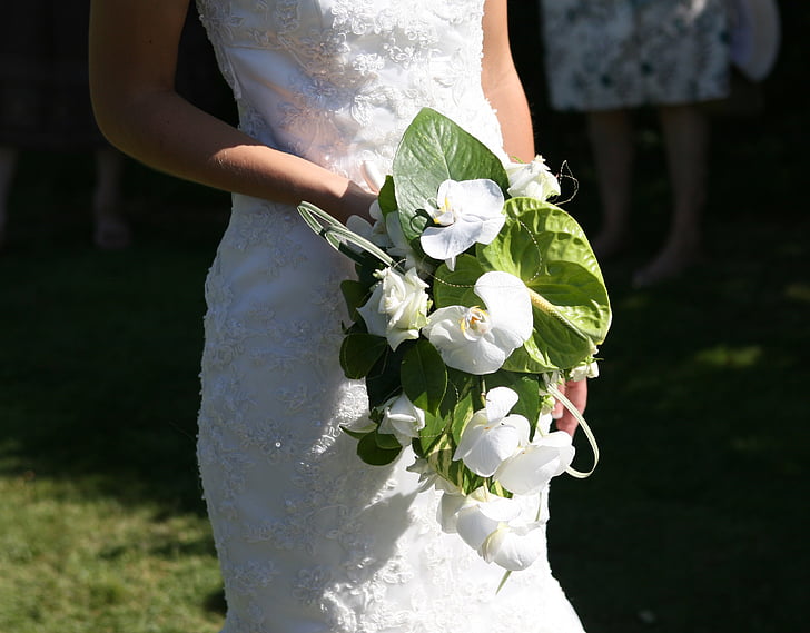 woman wearing white floral wedding dress holding white flowers