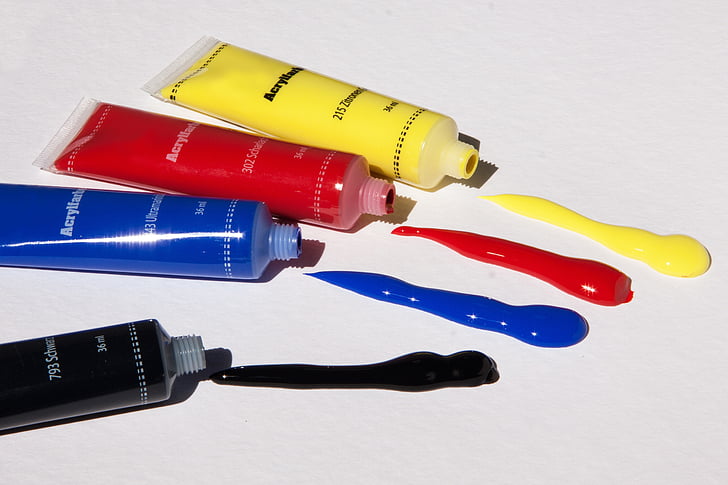 four yellow, red, blue, and black color labeled soft tube bottles