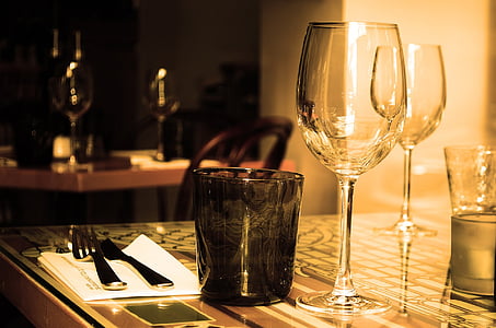 two clear wine glass and black tinted drinking glass on table