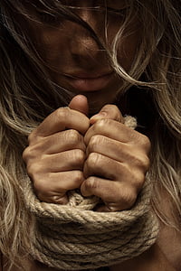 woman's hands tied with a rope