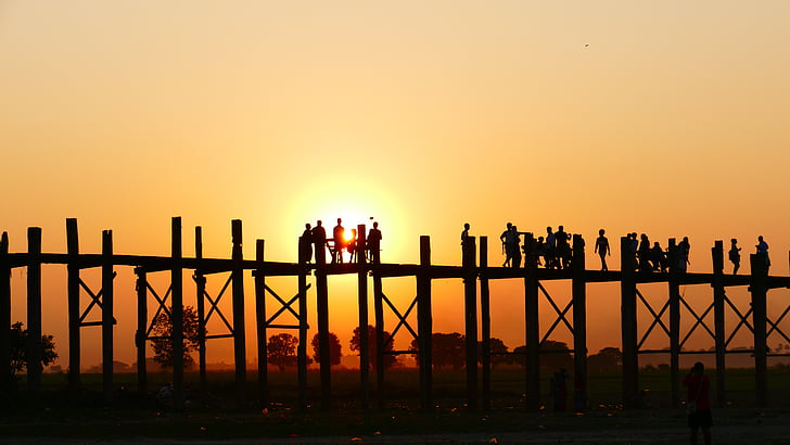 silhouette of people on wooden dock during sunset