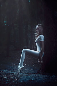 woman in white leggings sitting beside the tree