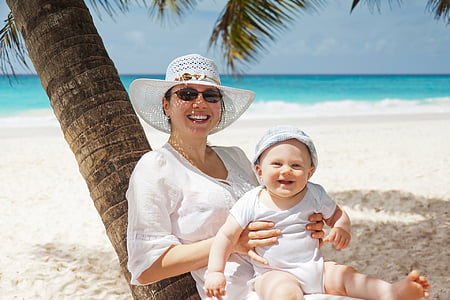 woman smiling wearing sun hat holding a smiling baby sitting on her lap