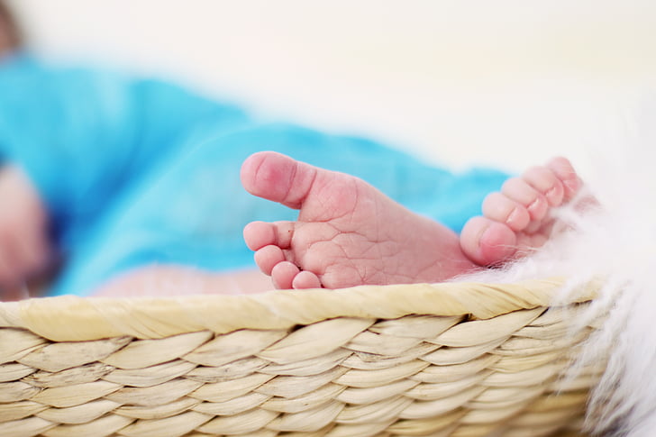 baby's feet on beige wicker basket