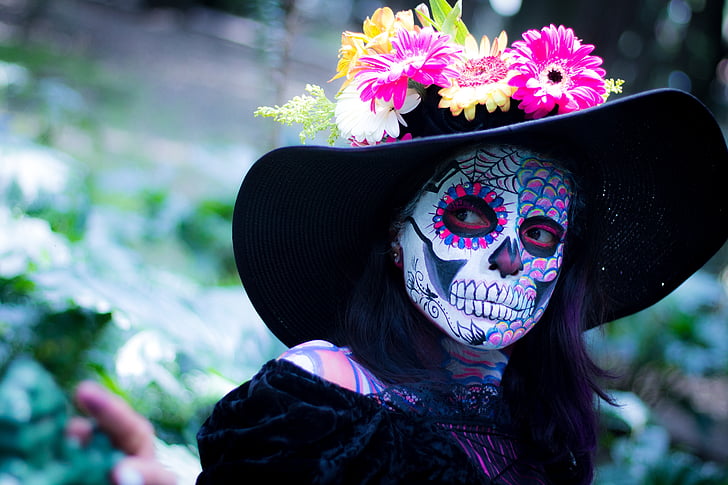 woman in black dress wearing black hat with sugar skull face paint