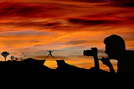 silhouette of man using camera during sunset