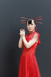 woman wearing red cap-sleeved dress with hair sticks