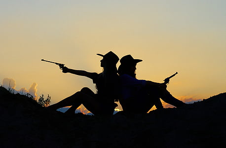 silhouette of two cowgirl holding pistols